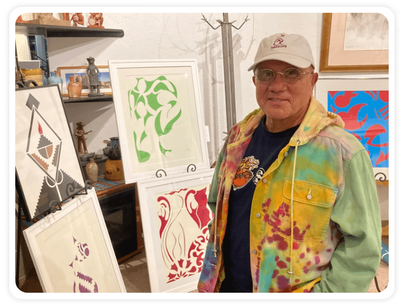 Man standing with colorful artwork display.