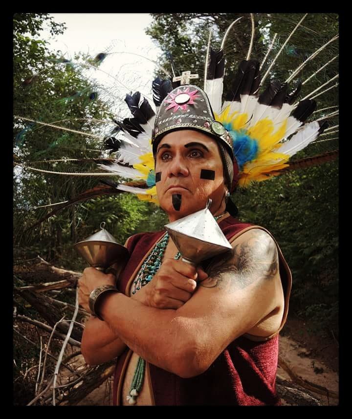 Person in ceremonial attire holding rattles.